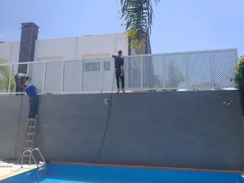 Claustra en aluminium ajouré posé en brise-vue au-dessus du mur d'une piscine, villa à Rabat