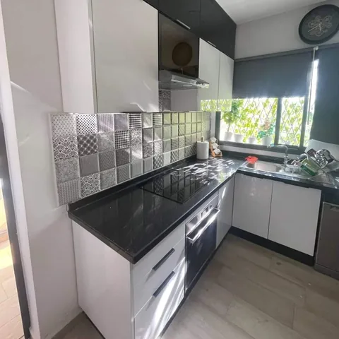 Cuisine sur mesure blanche avec plan de travail noir et crédence en carreaux, région de Rabat