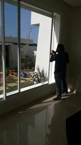 Grande baie vitrée coulissante en aluminium donnant sur le jardin d'une villa, à Rabat