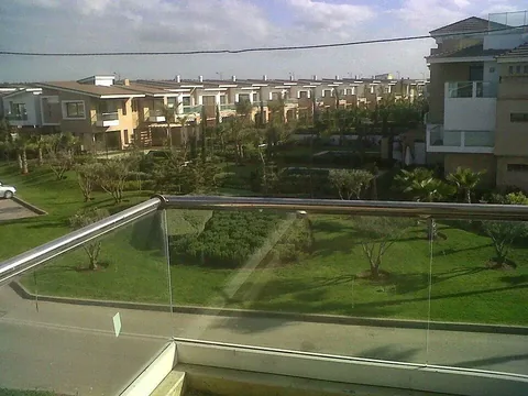 Garde-corps en verre avec main courante inox sur une terrasse donnant sur un parc, résidence à Rabat