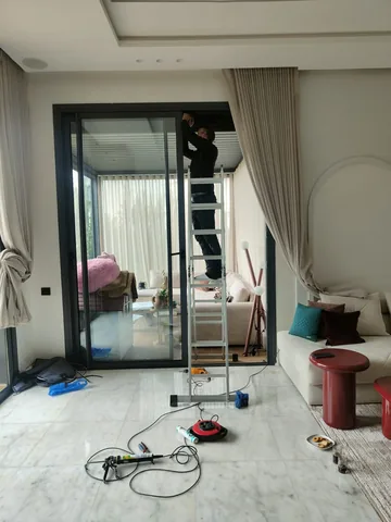 Pose d'une grande baie coulissante en aluminium noir dans le salon d'une villa, région de Rabat