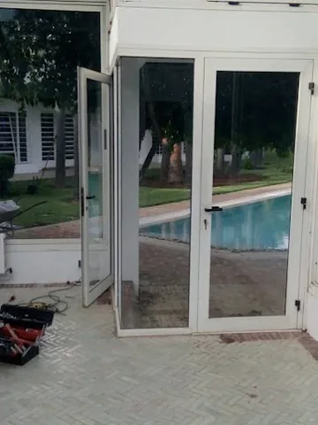 Porte-fenêtre double battant en aluminium blanc ouvrant sur une piscine, à Rabat