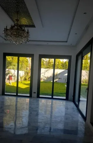 Portes-fenêtres en aluminium noir ouvrant le salon d'une villa sur le jardin, à Rabat