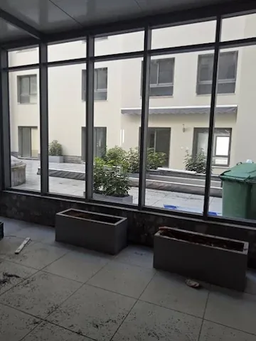 Véranda en aluminium noir à grandes baies vitrées, vue sur une résidence, à Rabat